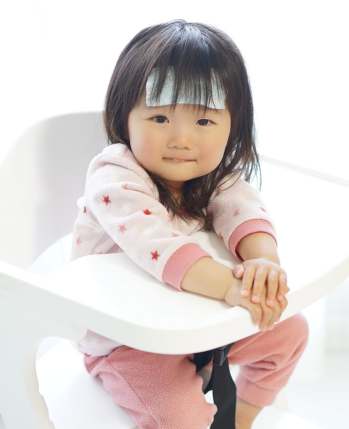 発熱時に冷却シートを貼って安静にしている幼い女の子の写真