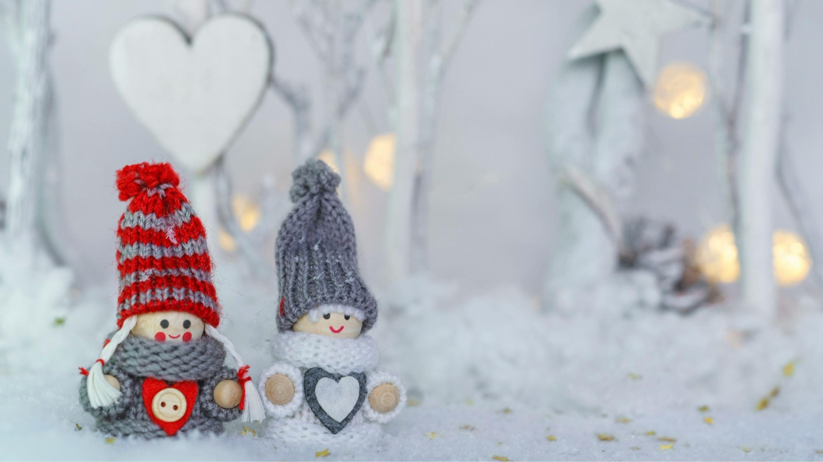 冬の雪景色の中に並ぶマフラー姿の小さな人形の写真